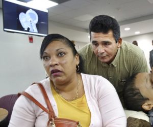 Emanuel Zayas, de 14 años _a la derecha_, será operado en el Hospital Infantil Holtz, dentro del Hospital Jackson Memorial, el 12 de enero de 2018, para retirarle un tumor de 4,5 kilos (10 libras) que le cubre el rostro. Junto a él, sus padres Noel Zayas y Melvis Vizcaínos hablan con los periodistas el viernes 22 de diciembre de 2017. En la parte superior izquierda de la fotografía se encuentra una imagen del rostro de Emanuel en rayos X. (C.M. Guerrero/Miami Herald vía AP)